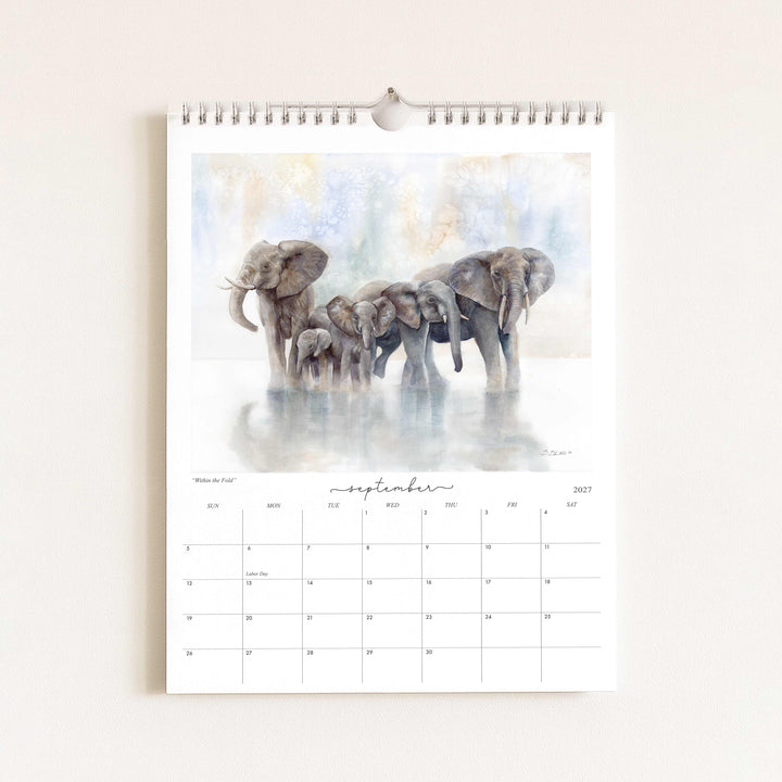 Watercolor painting of an elephant herd titled "Within the Fold," featured in the 2027 wildlife calendar